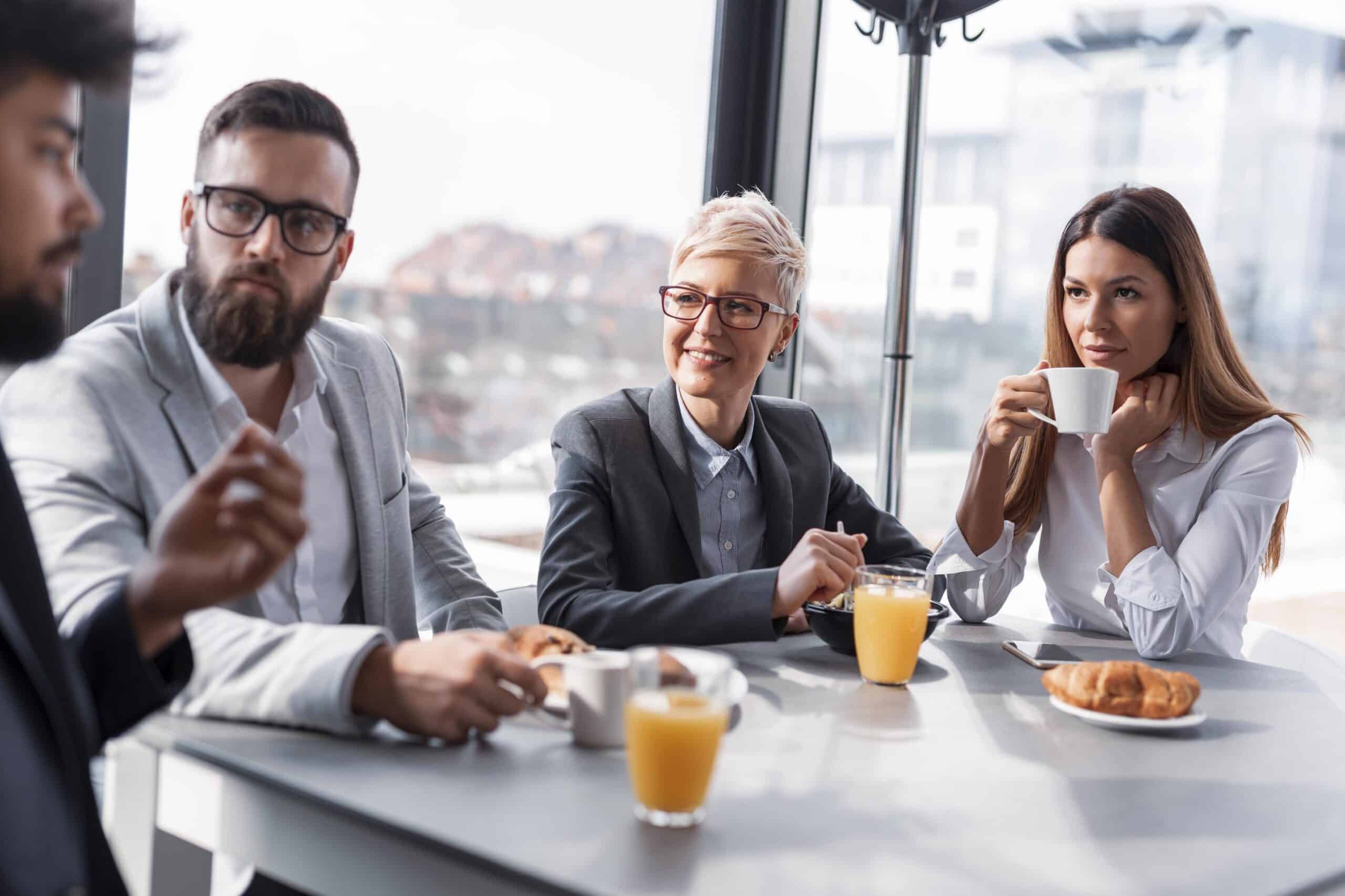 Group of business people having breakfast in company's restaurant. Focus on the women