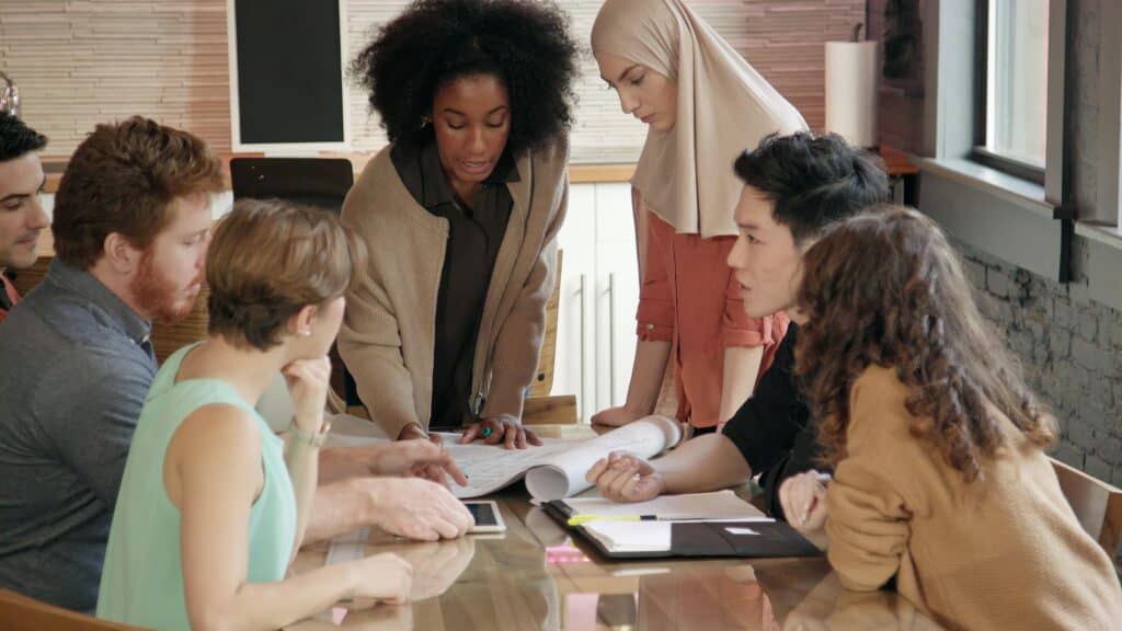 Medium close up of a young African-American woman leading a multi-ethnic team meeting.