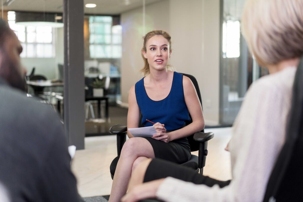 Confident young businesswoman planning strategy with professionals in board room. Multi-ethnic entrepreneurs are discussing during meeting. They are sitting at creative office.